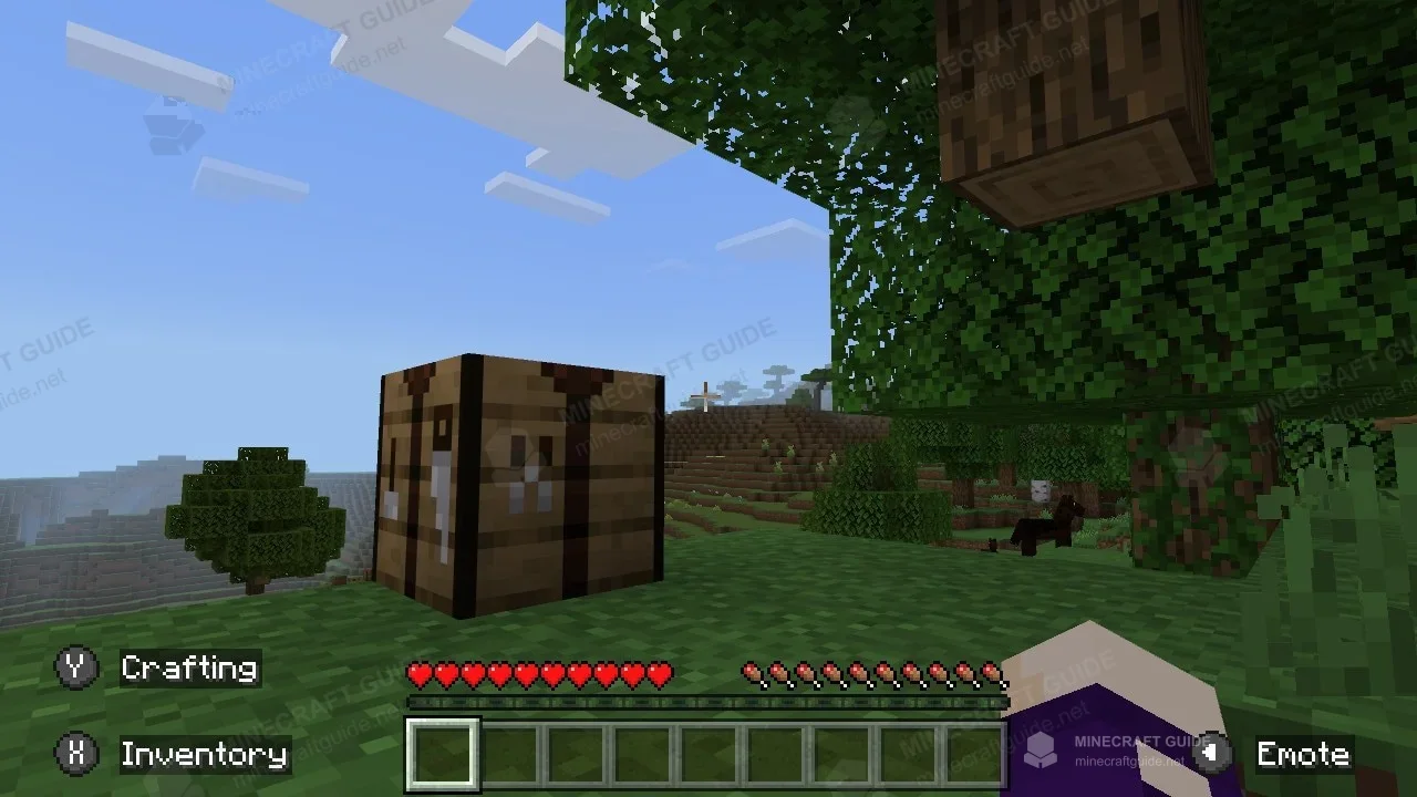 A crafting table on grass beside a tree, with controller prompts