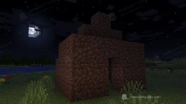 A small dirt shelter with a door at night